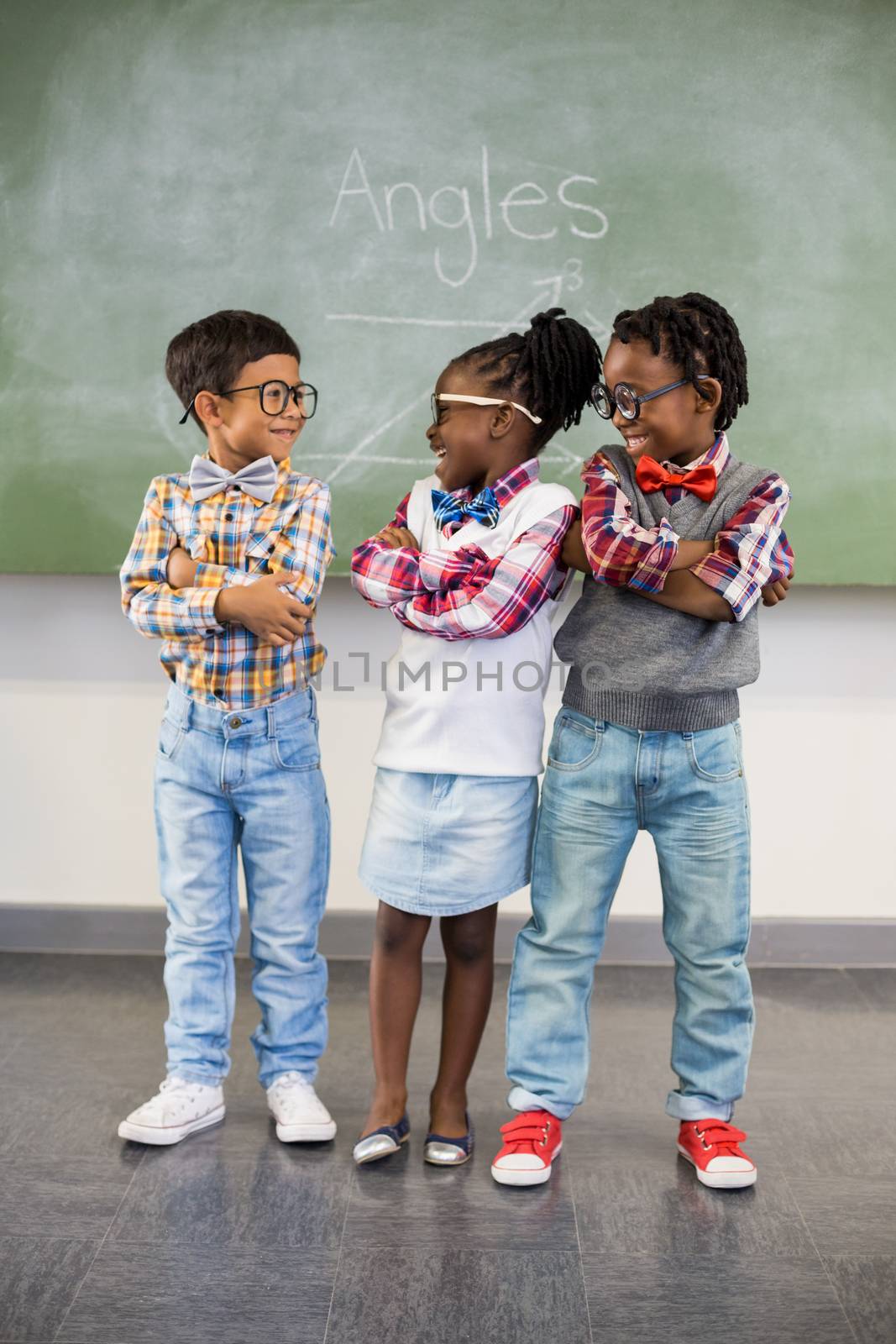 Three school kids talking to each other in classroom by Wavebreakmedia