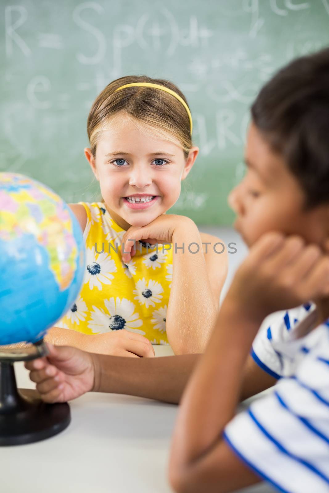 Happy school kids with globe in classroom at school