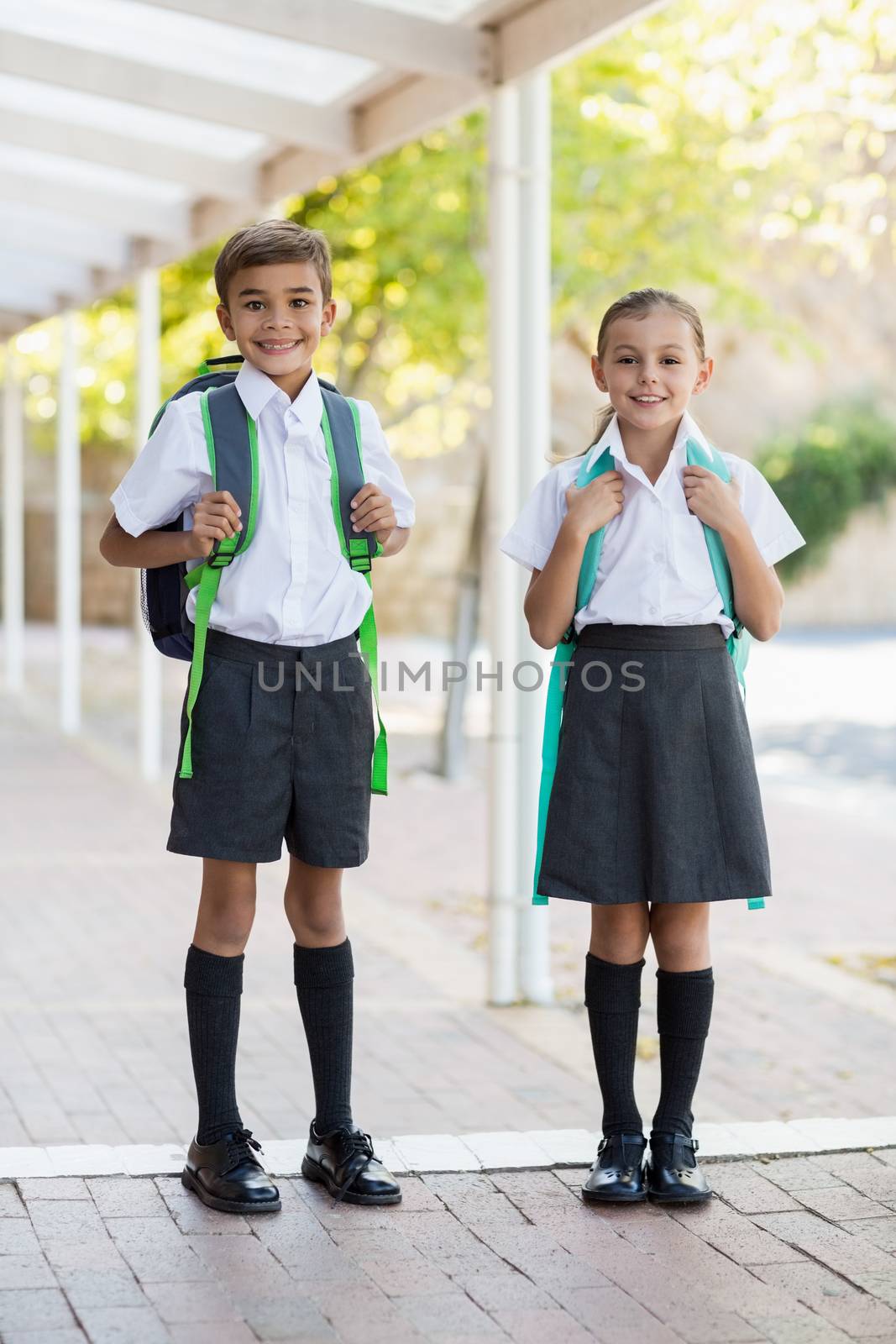 Smiling school kids standing in corridor by Wavebreakmedia
