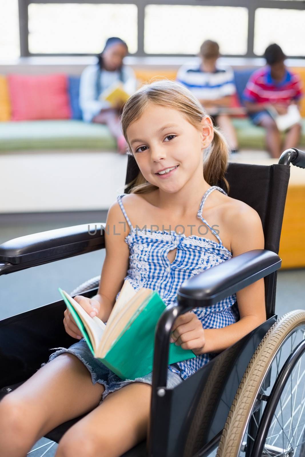 Portrait of disabled school girl reading book in library by Wavebreakmedia