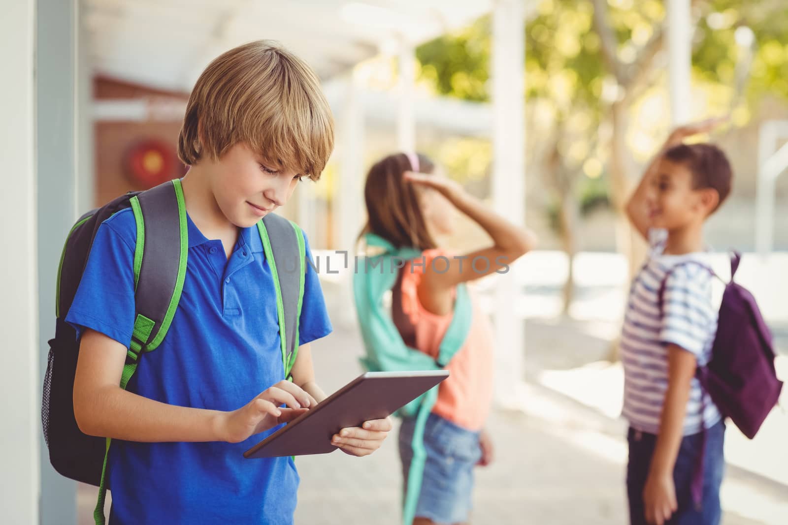 Schoolboy using digital tablet in school corridor by Wavebreakmedia