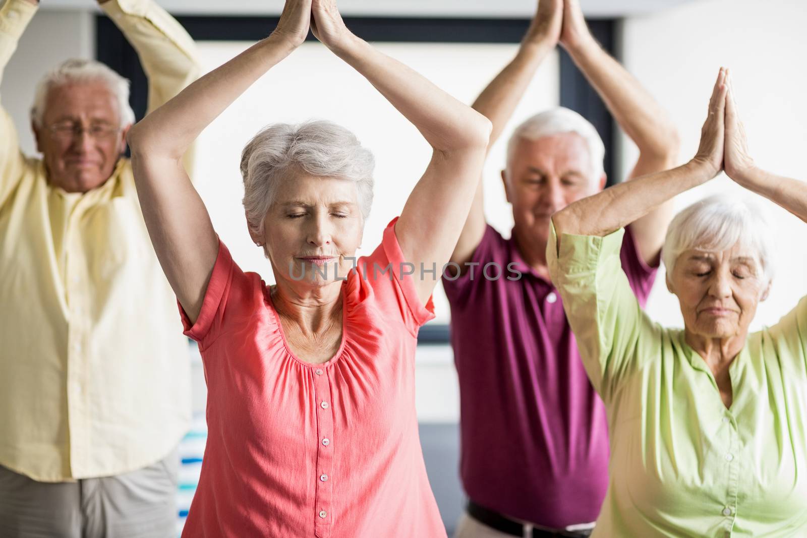 Seniors doing yoga with closed eyes  in a retirement home