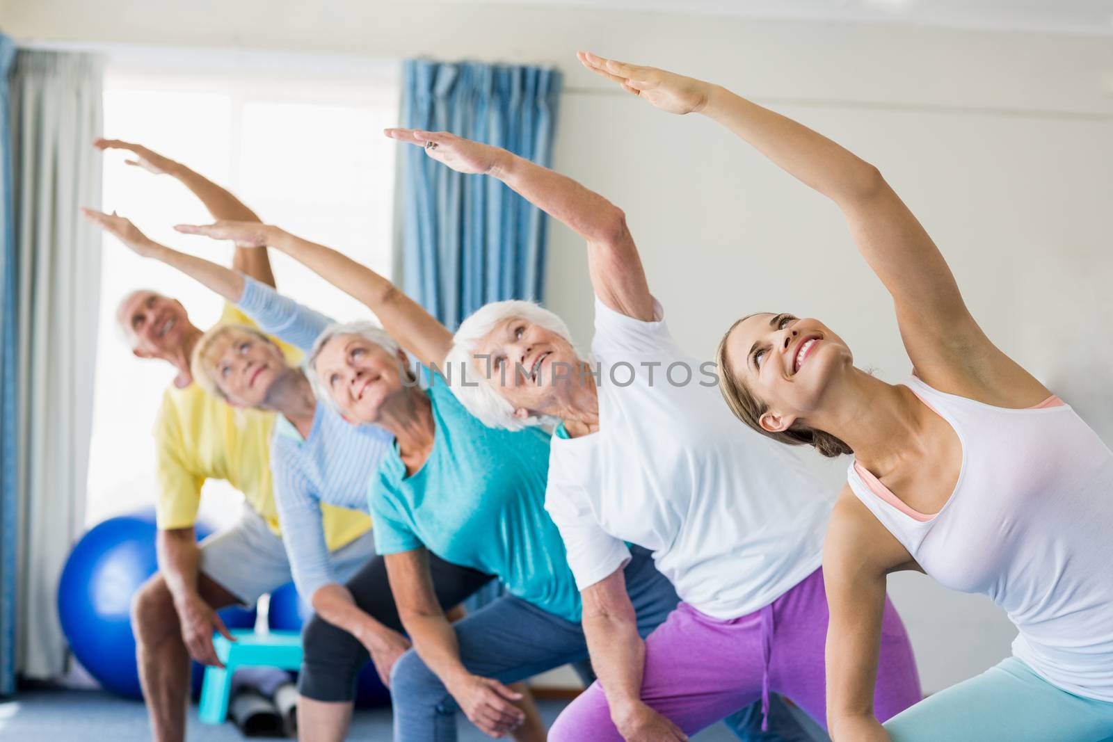 Instructor performing yoga with seniors during sports class