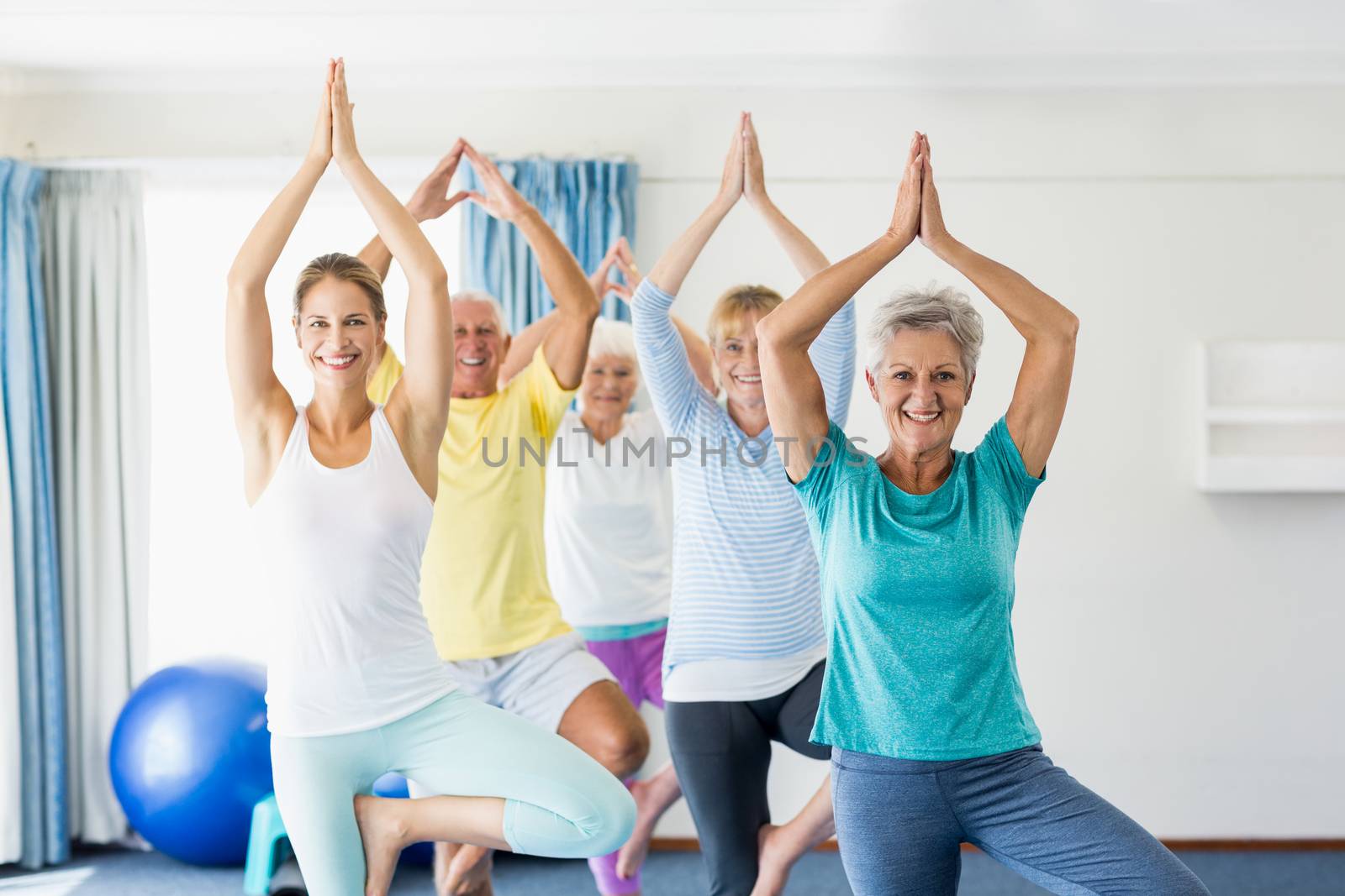 Instructor performing yoga with seniors during sports class