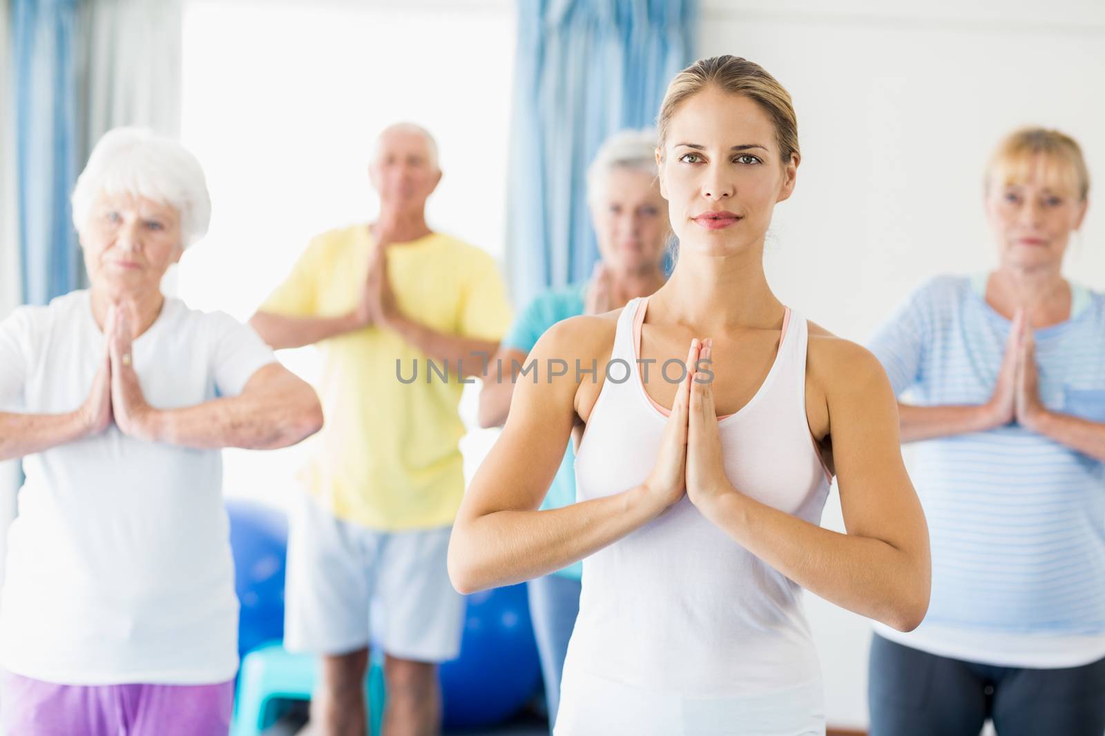 Instructor performing yoga with seniors during sports class