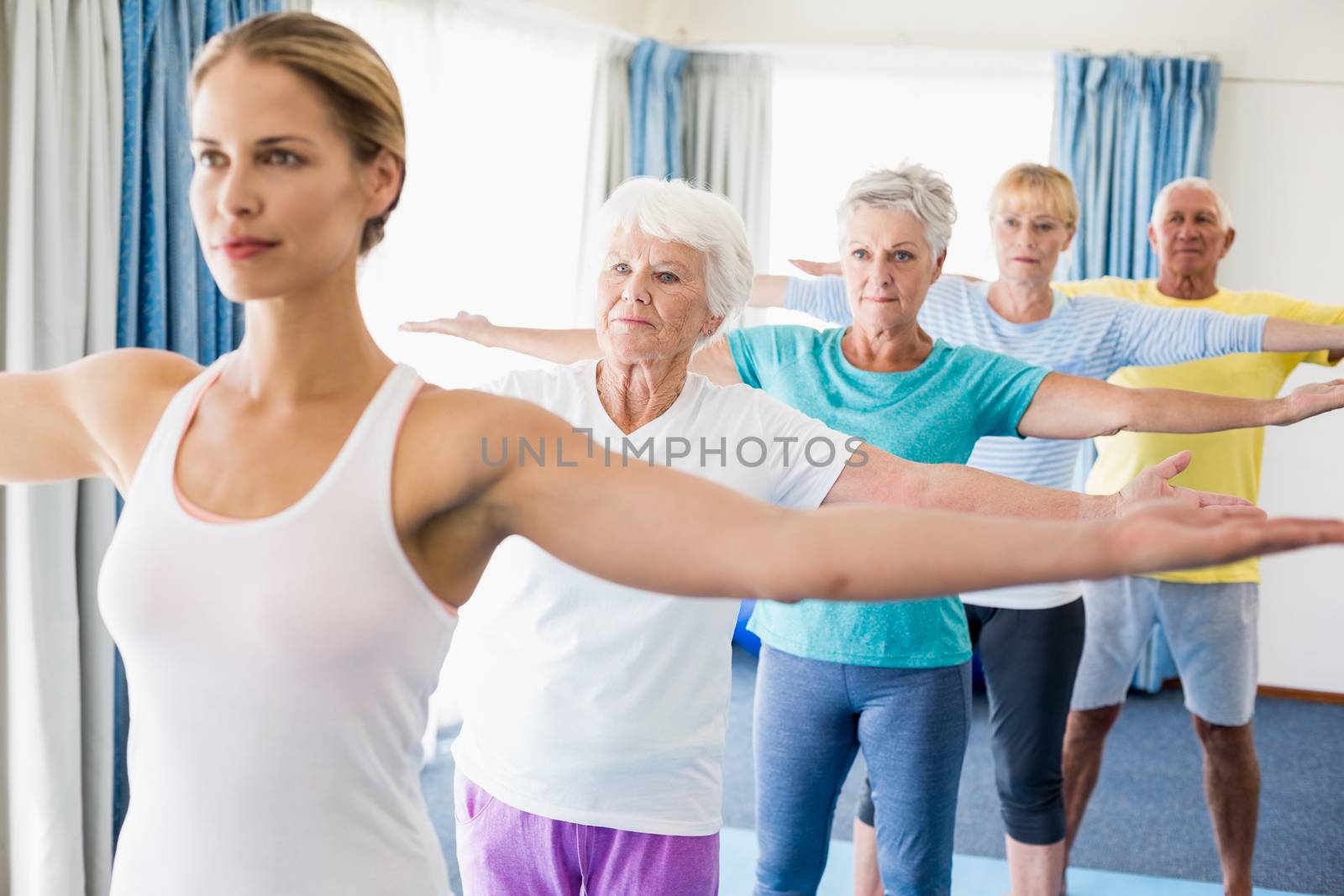 Instructor performing yoga with seniors during sports class