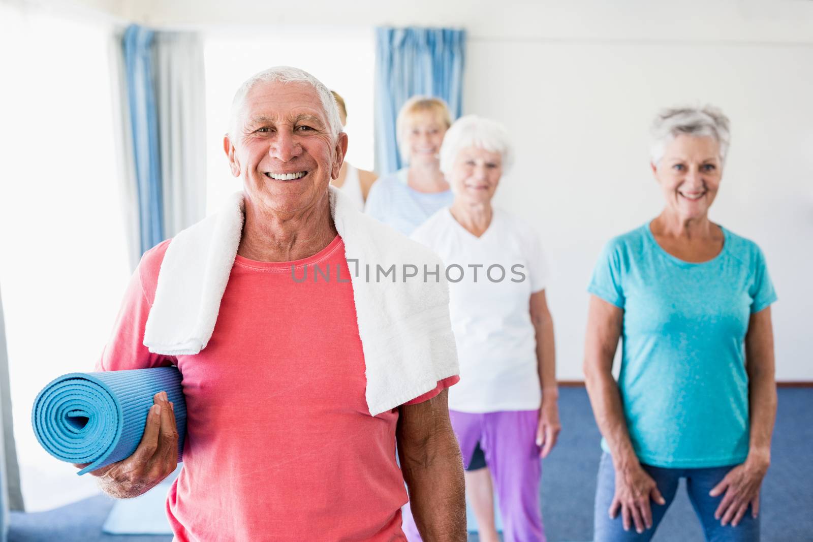 Senior man holding yoga mat during sports class