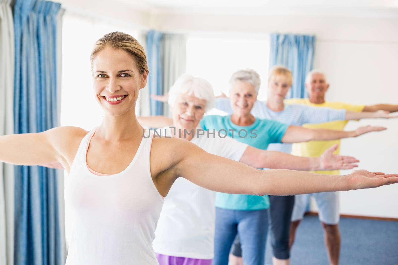 Instructor performing yoga with seniors during sports class