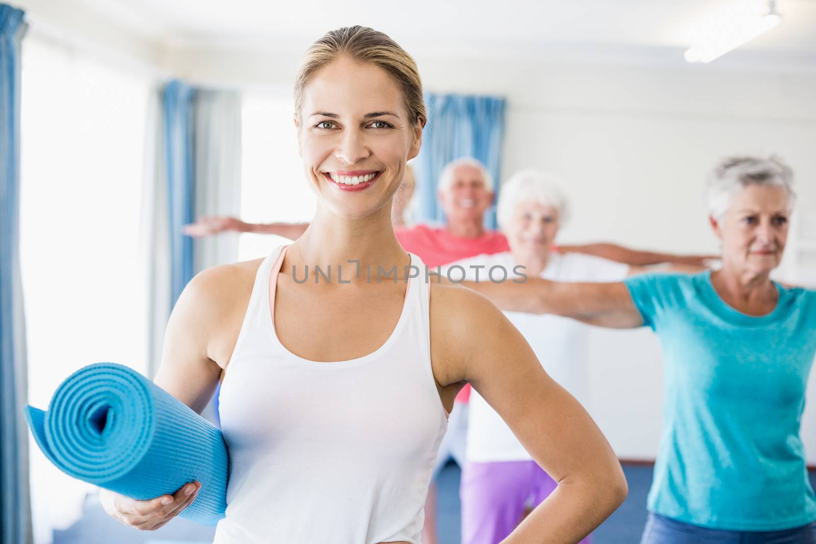 Instructor holding yoga mat during sports class