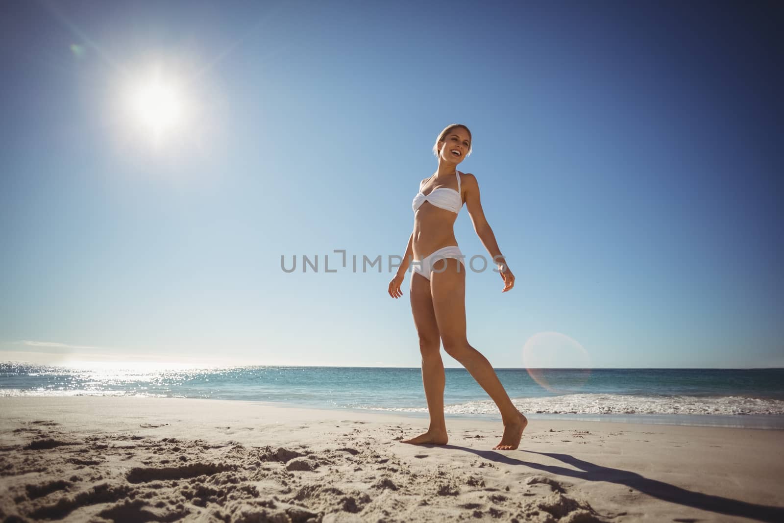 Beautiful young woman walking on beach in summer