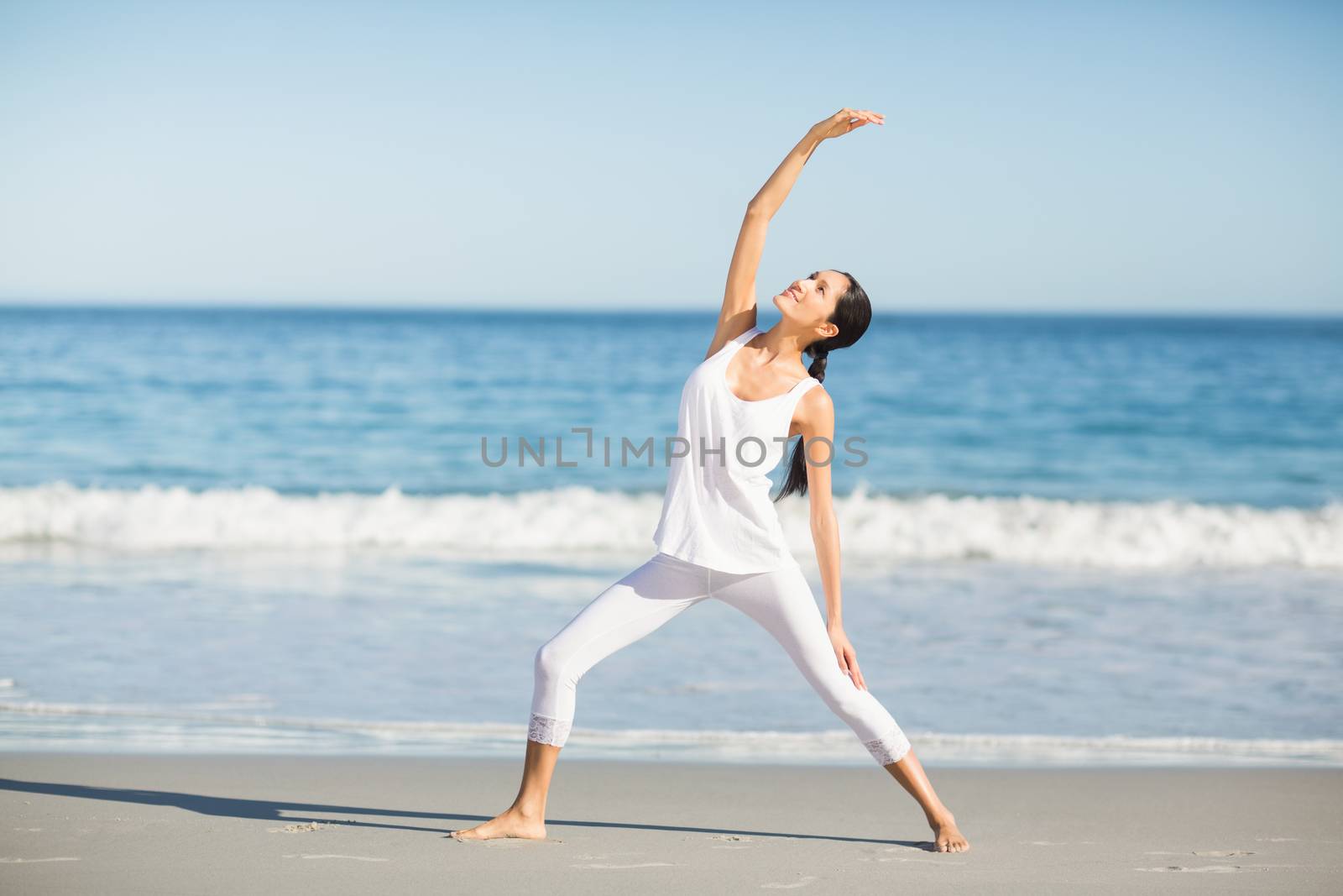 Woman doing yoga on the beach on a sunny day