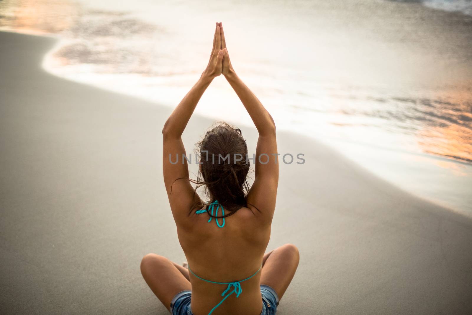 Woman performing yoga on the beach 