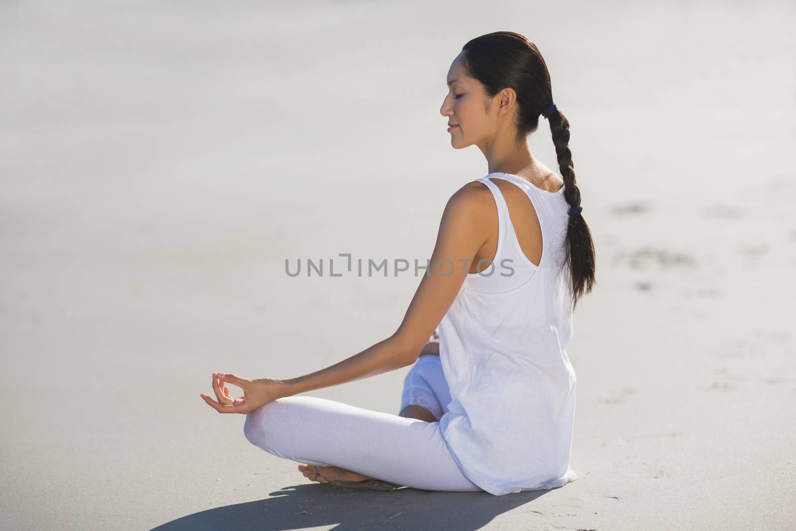 Young woman performing yoga on the beach