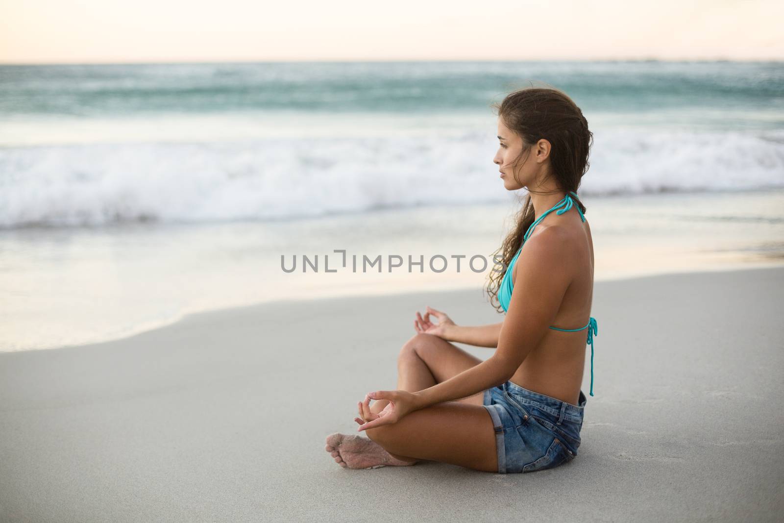 Young woman performing yoga on the beach