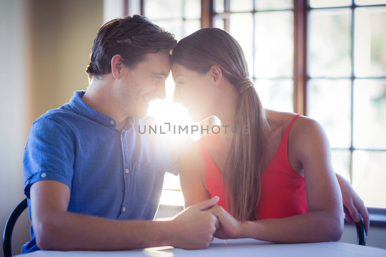 Romantic couple holding hands and sitting face to face at restaurant