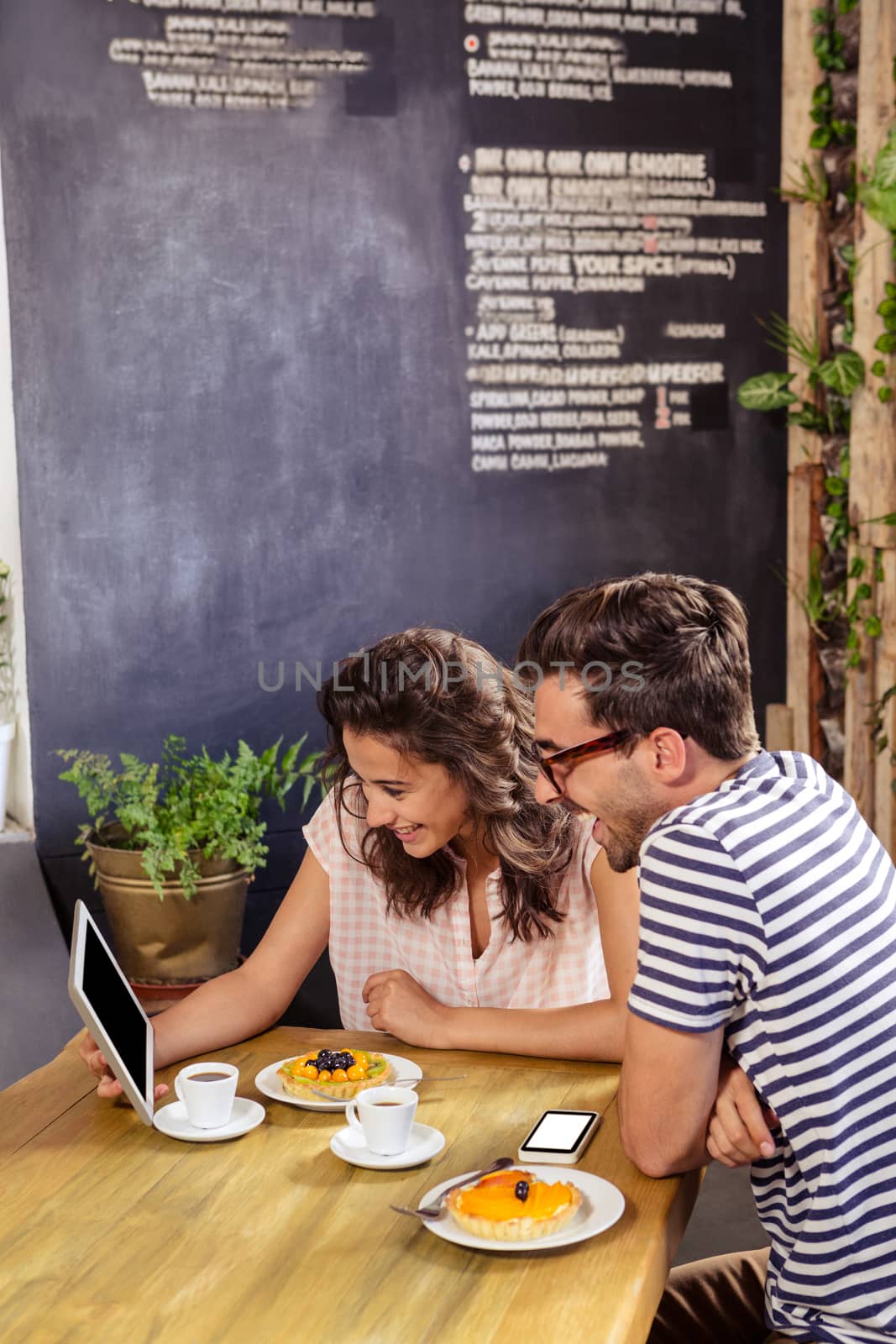 Young couple using digital tablet in cafeteria by Wavebreakmedia