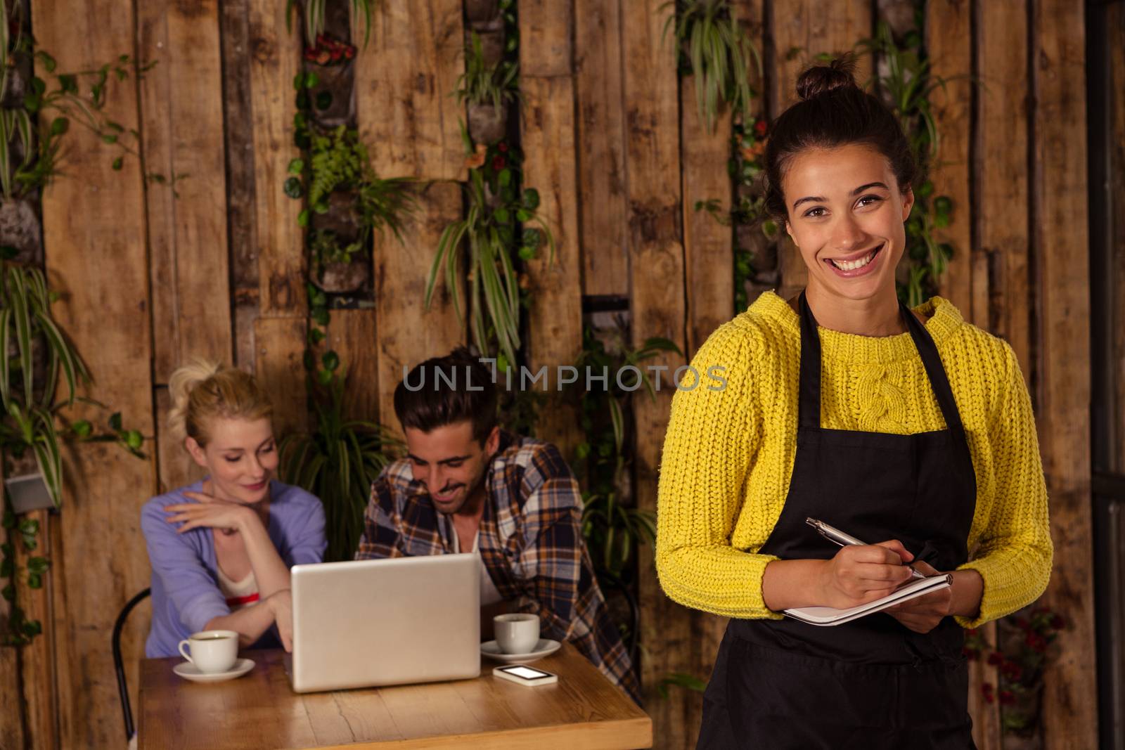 A waitress is taking the order in front of the two friends in a coffee shop