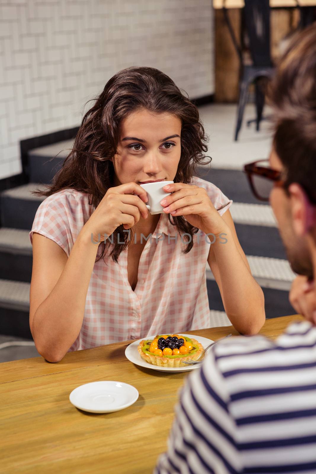 Young woman talking to man while having coffee in cafeteria