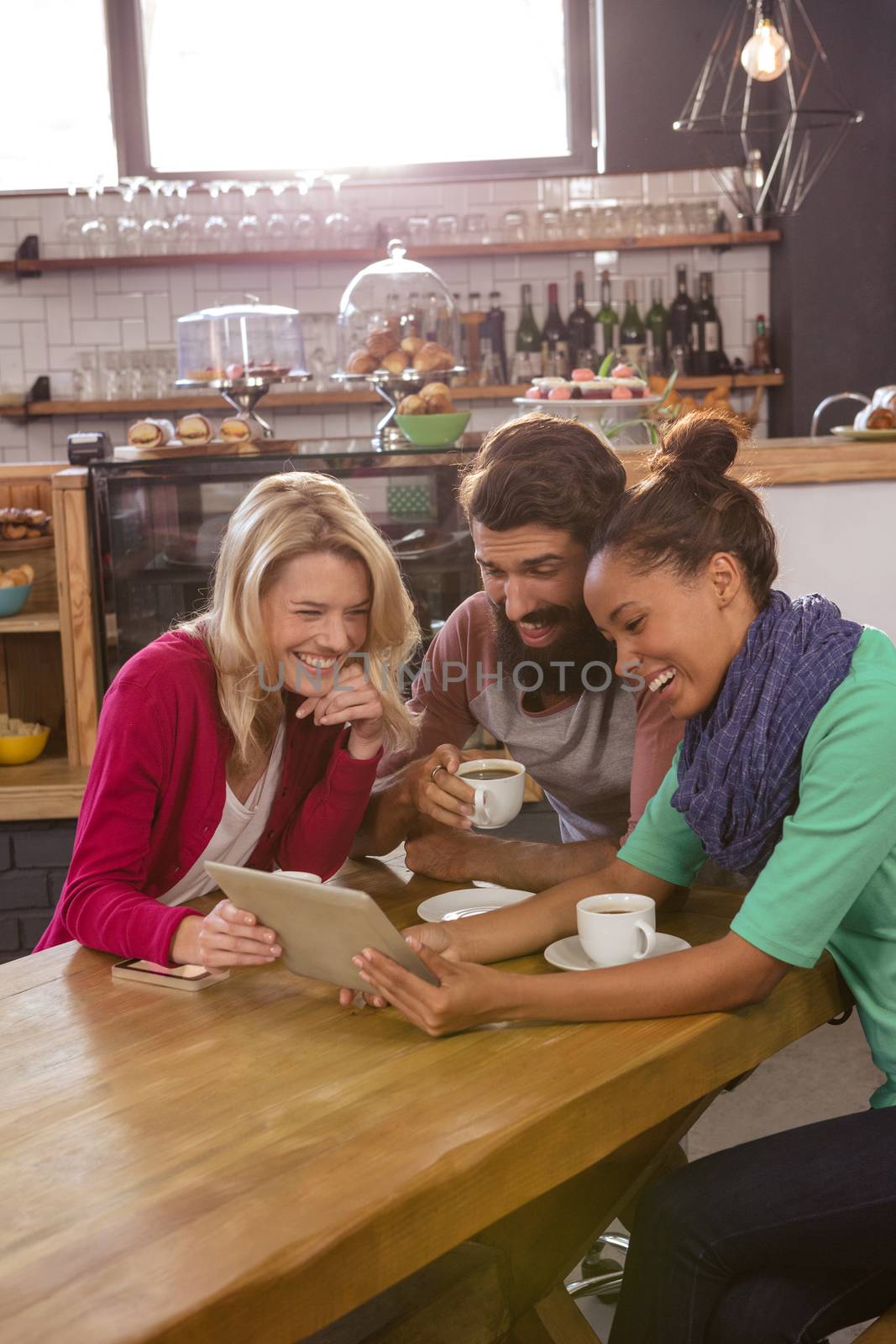 Friends using a tablet sitting in the cafe