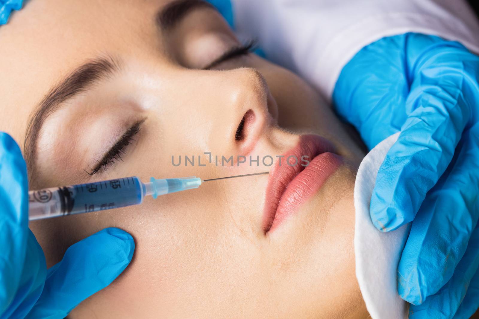 Woman receiving botox injection on her lips by Wavebreakmedia