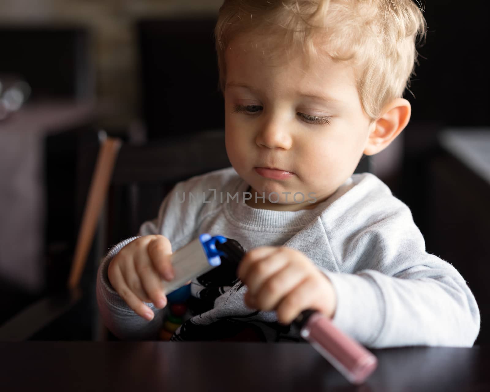 Baby boy sitting in high chair and plays with objects at chinese restaurant.portrait horizontal.