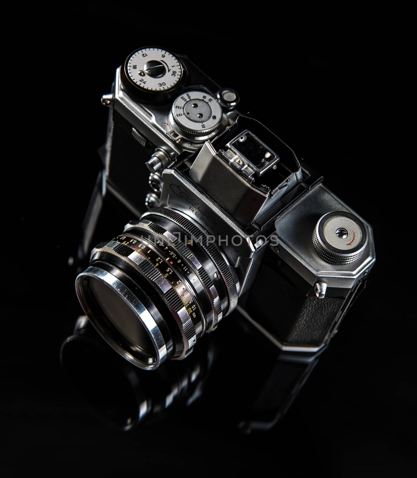 Black and silver Photo Camera standing on a glass pane