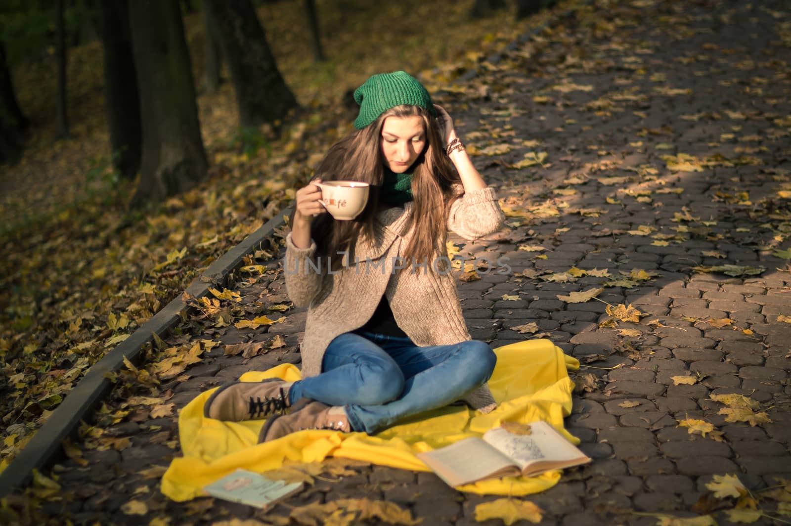 girl with a cup of coffee sitting in autumn Park