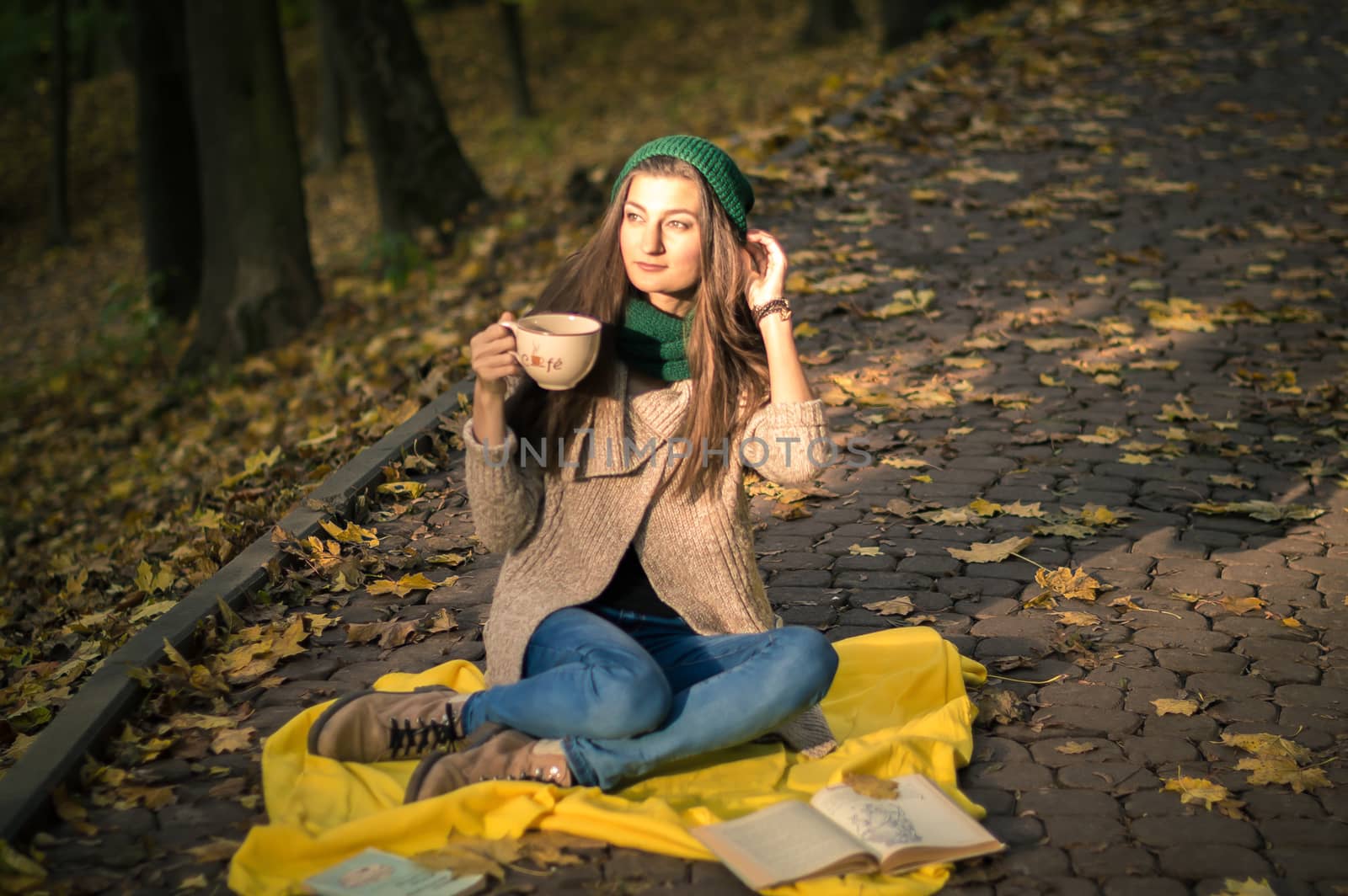 girl with a cup of coffee sitting in autumn Park