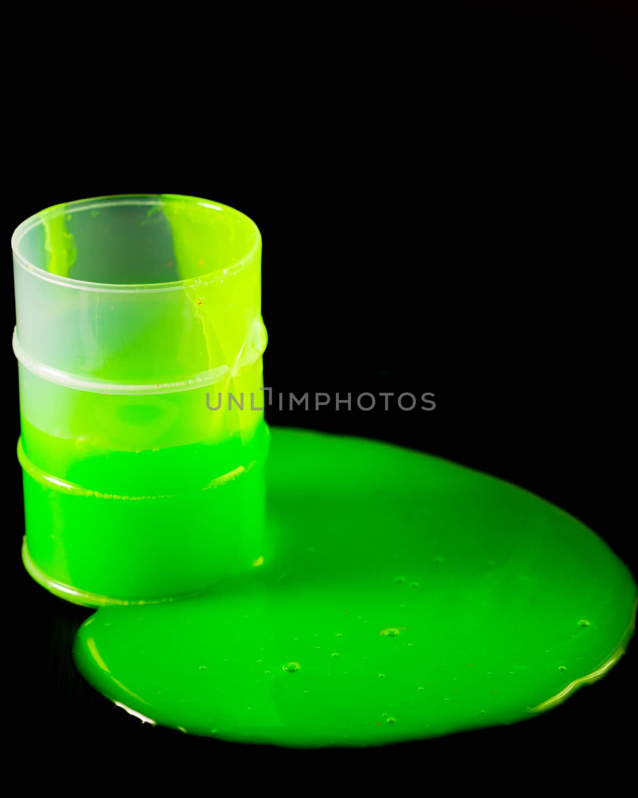 Green slime spllling out of barrel on black background