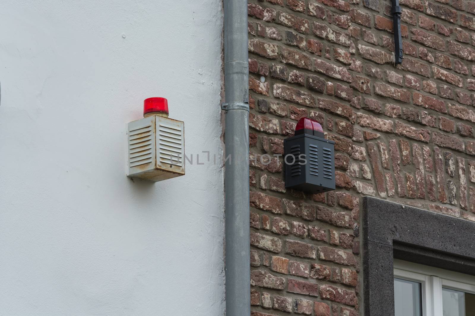 Two alarm systems with warning lights on a house wall