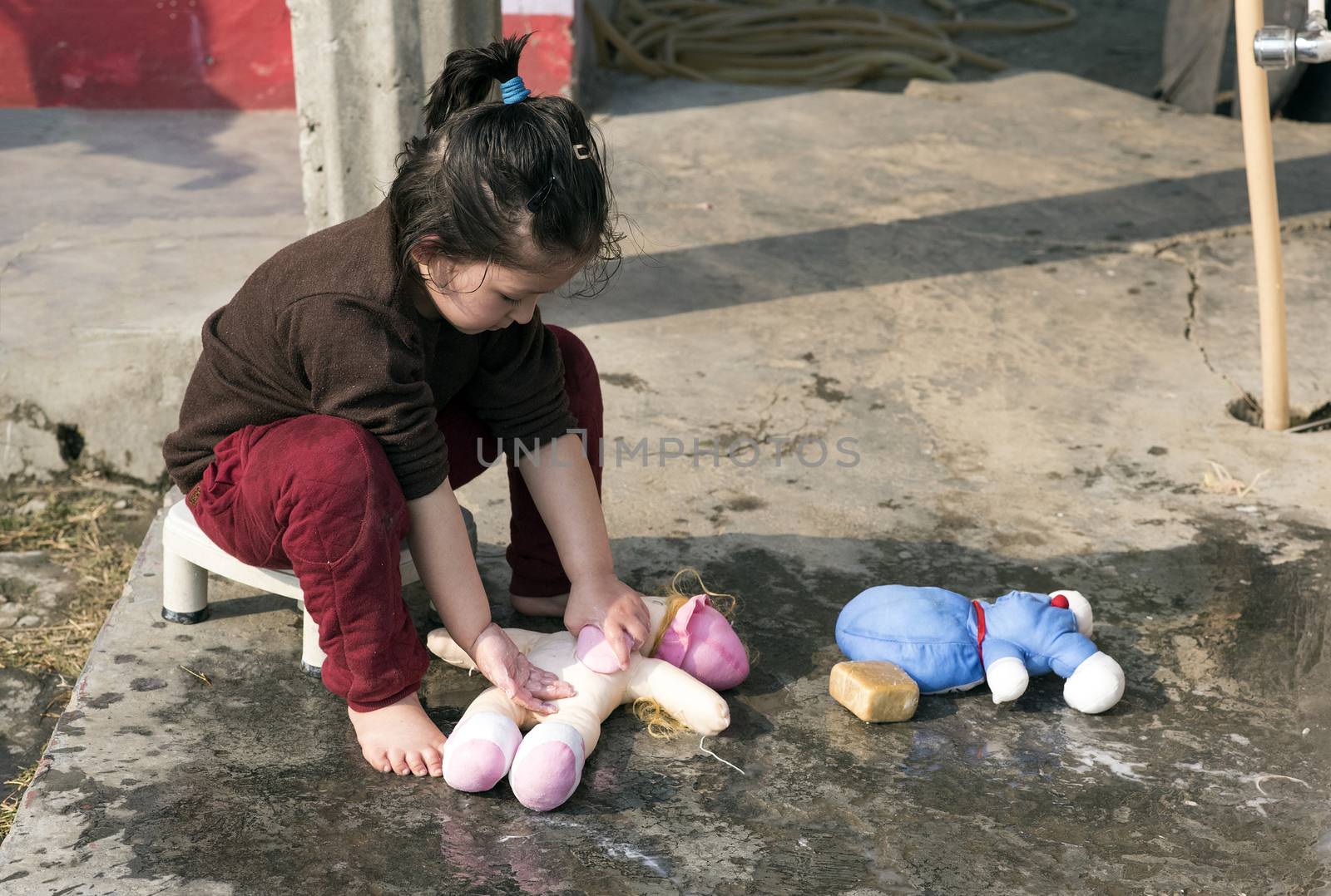 Cute little girl washing her doll outdoor