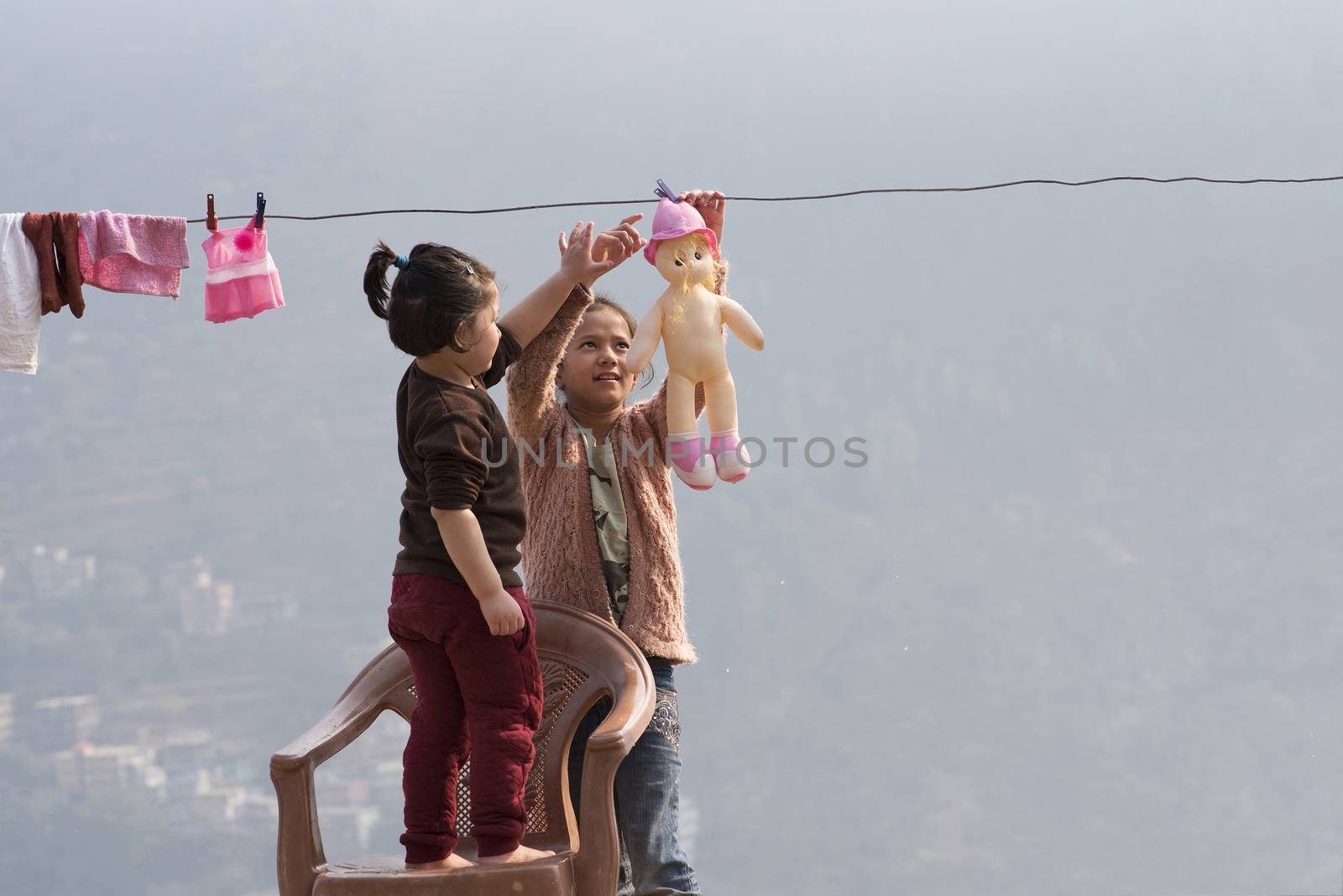 Kids wash their dolls and hang them out to dry on the clothesline. Children doing laundry and playing outdoors.