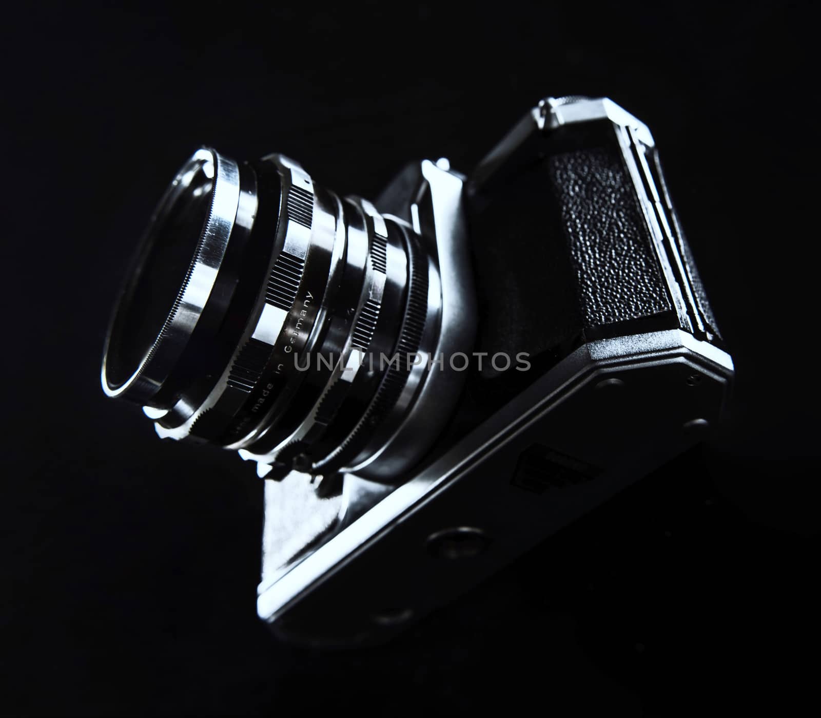 Black and silver Photo Camera standing on a glass pane