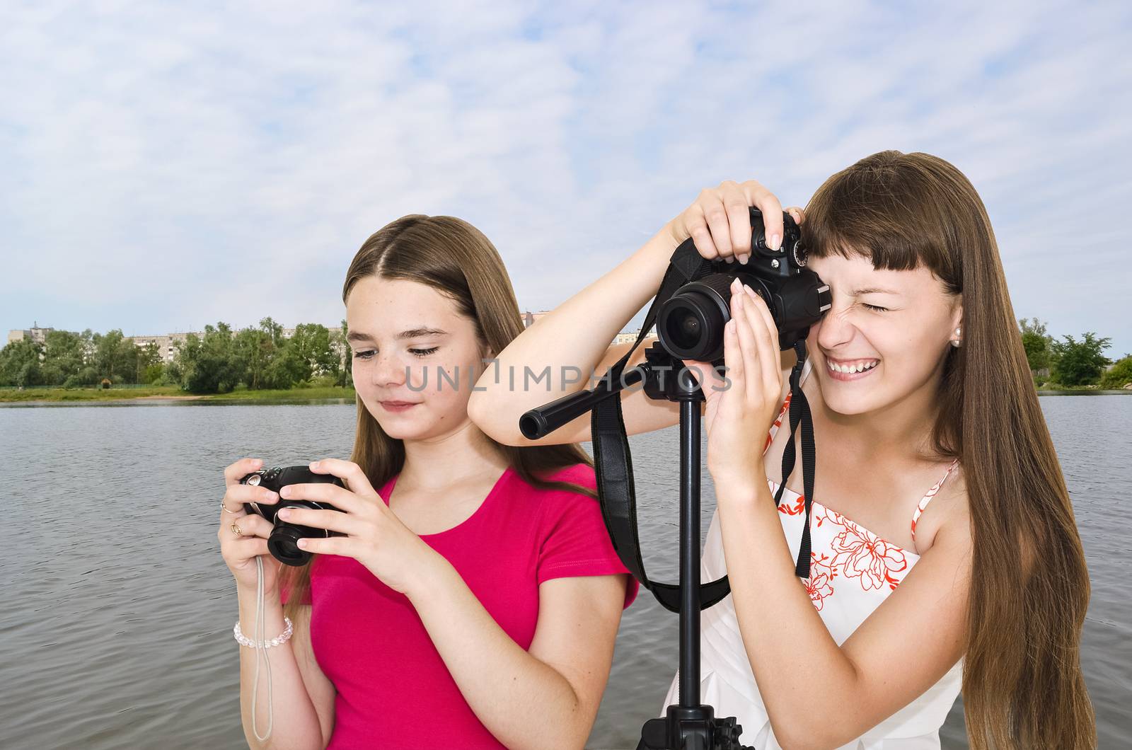 Two funny photographer teen girls outdoors by the river