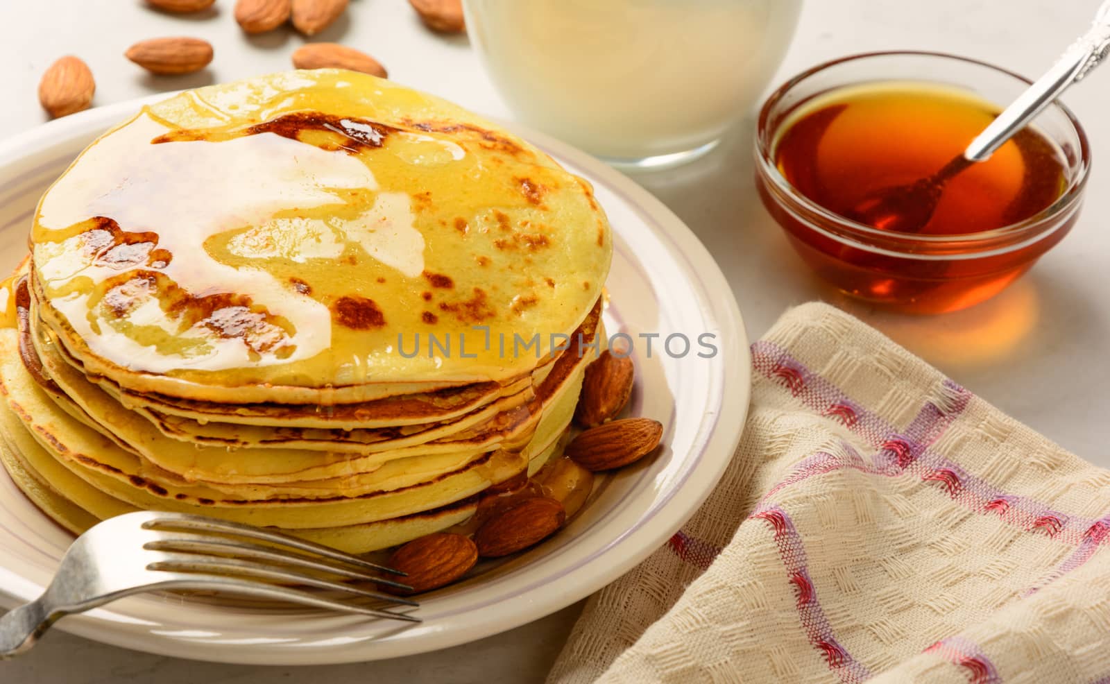 Pancakes with honey and almond on a white background