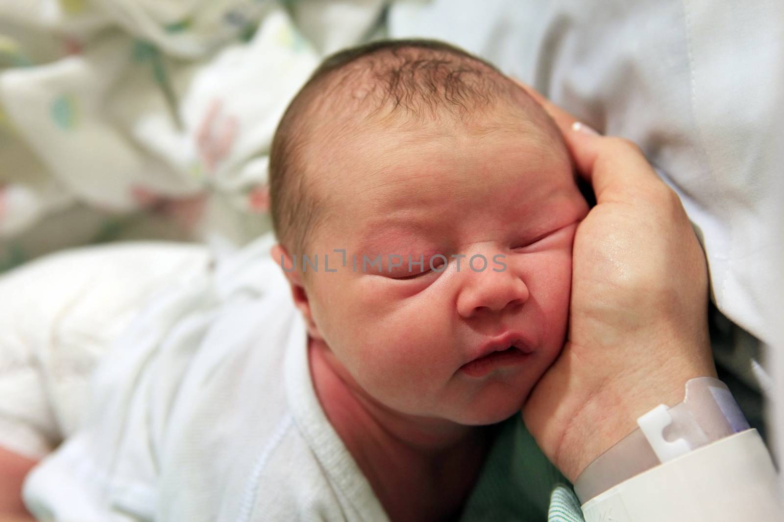 Sleeping newborn baby in the arms of my mother in hospital