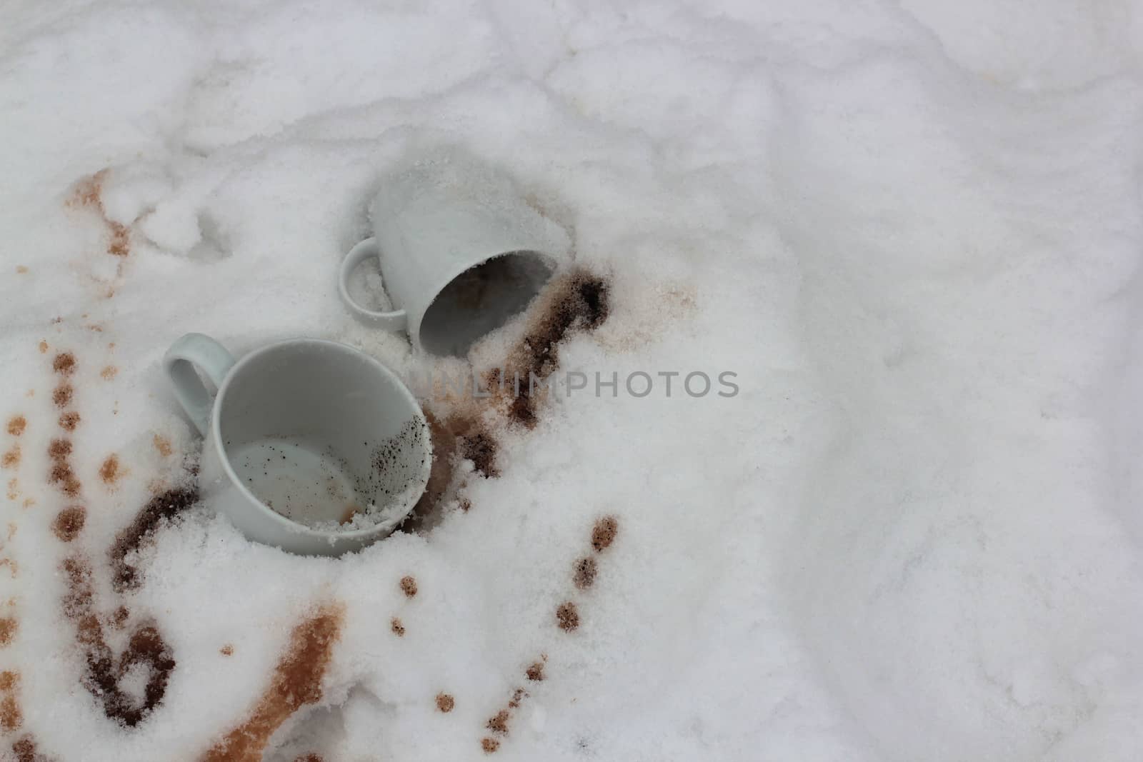 two white cups and the poured coffee in snow