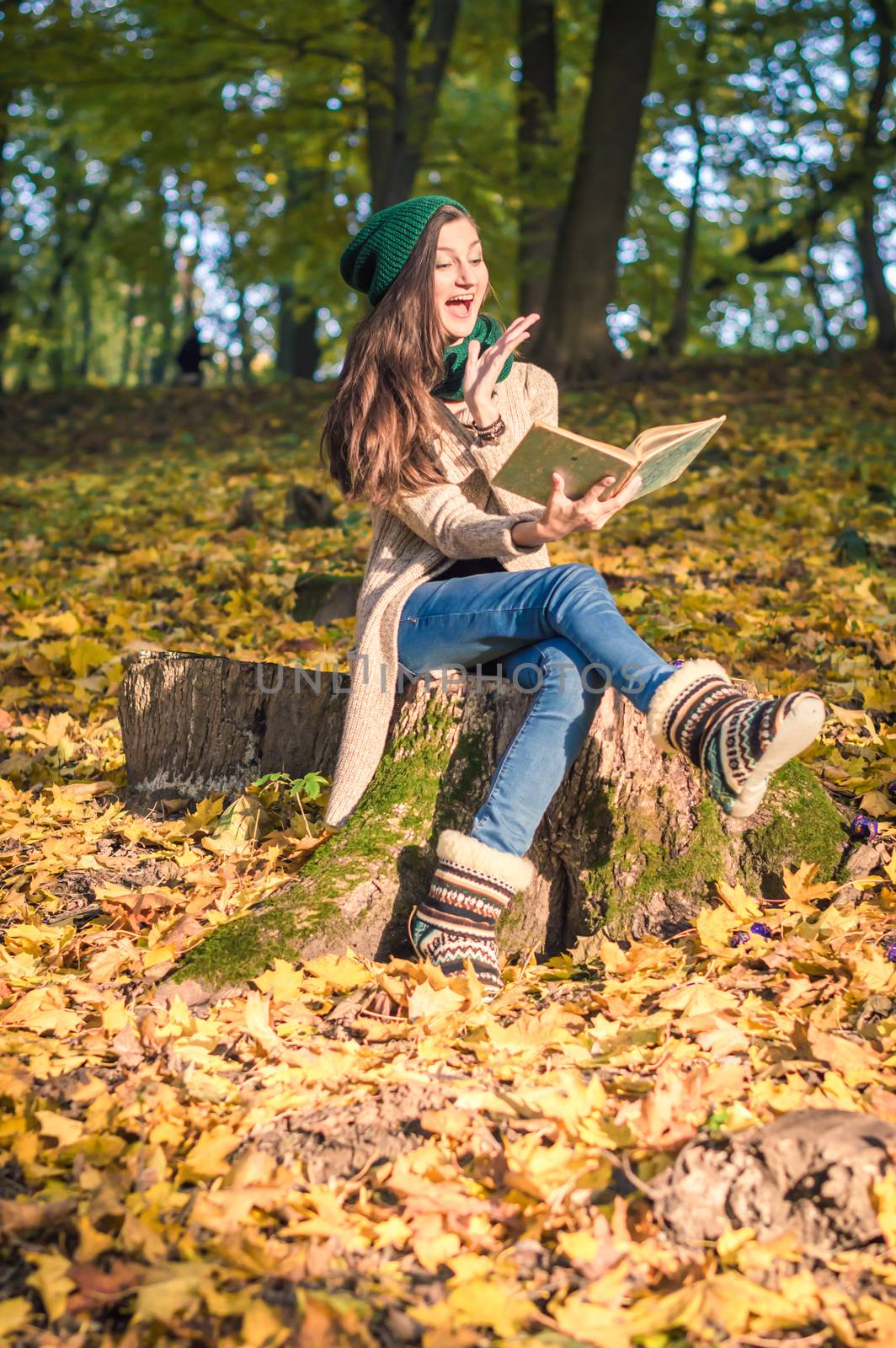 girl sits on the stump in the park, reading a book