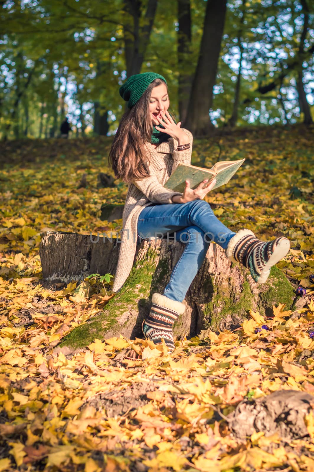 girl sits on the stump in the park, reading a book