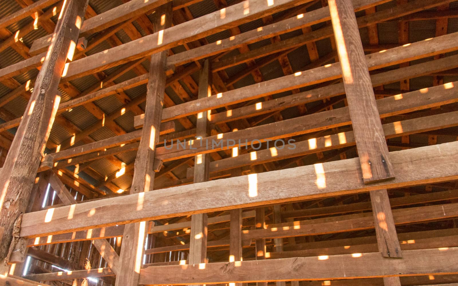 Bits of light shining through the cracks, illuminating the interior of a barn.