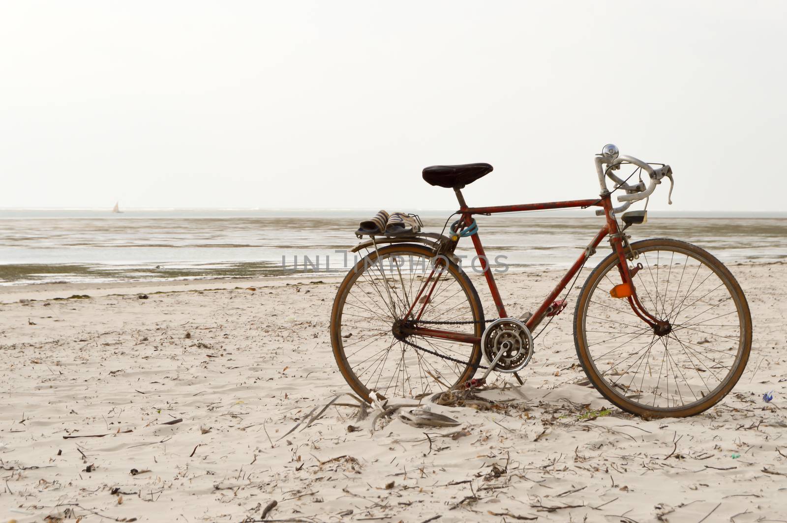 Red and white racing bike on the white sand of bamburi beach in Mombasa, Kenya