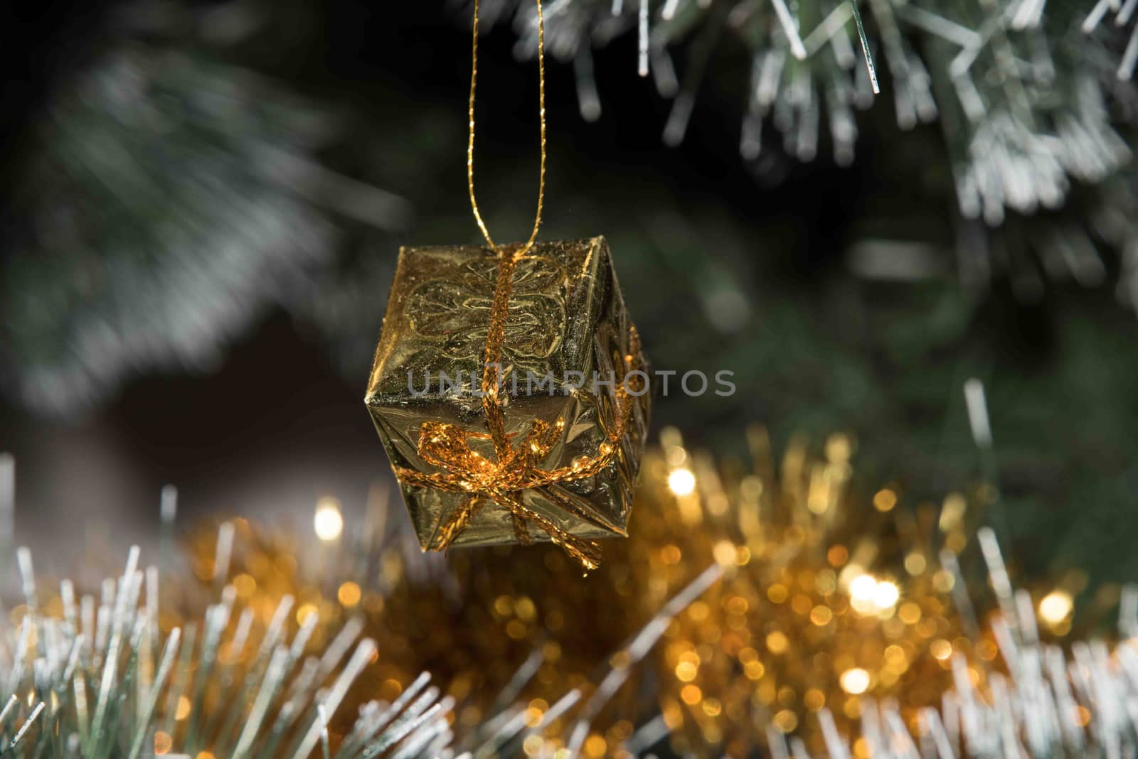 Present for the New Year's branch. Golden Christmas decorations. Close-up. Gift box on Christmas tree lights background