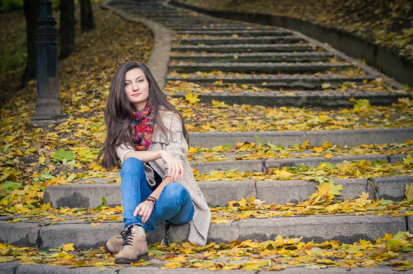 girl sitting on stone steps in autumn Park