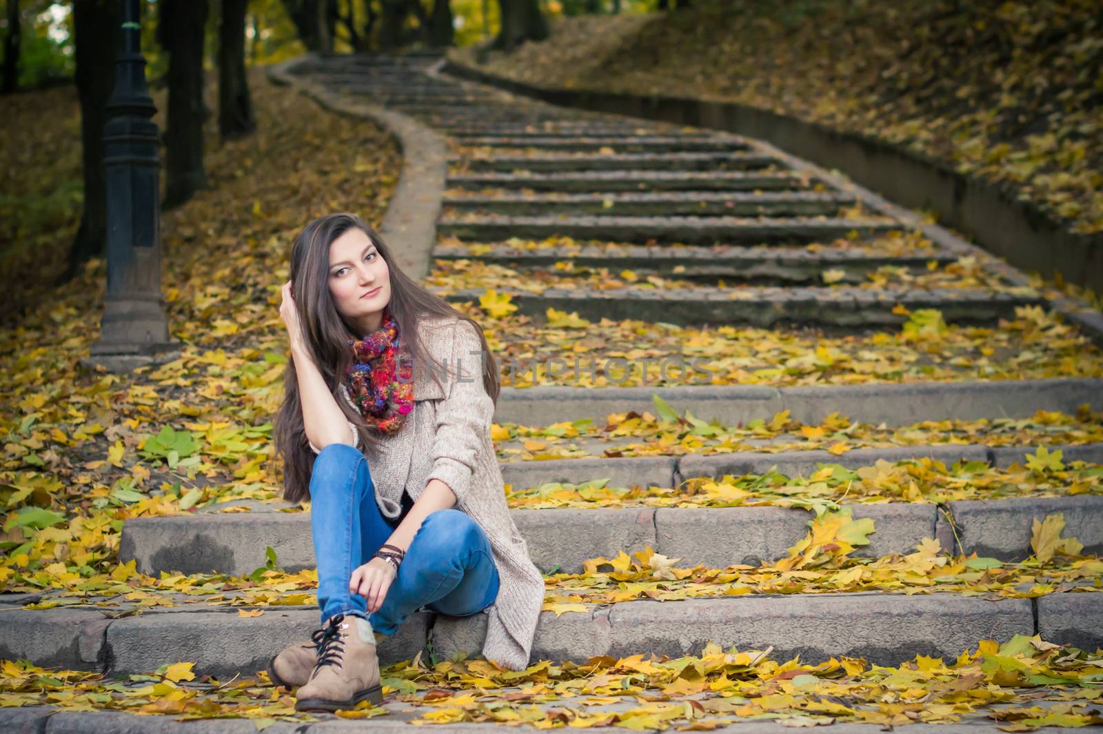 girl sitting on stone steps in autumn Park