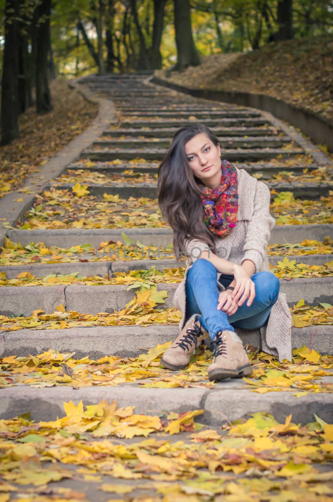 girl sitting on stone steps in autumn Park