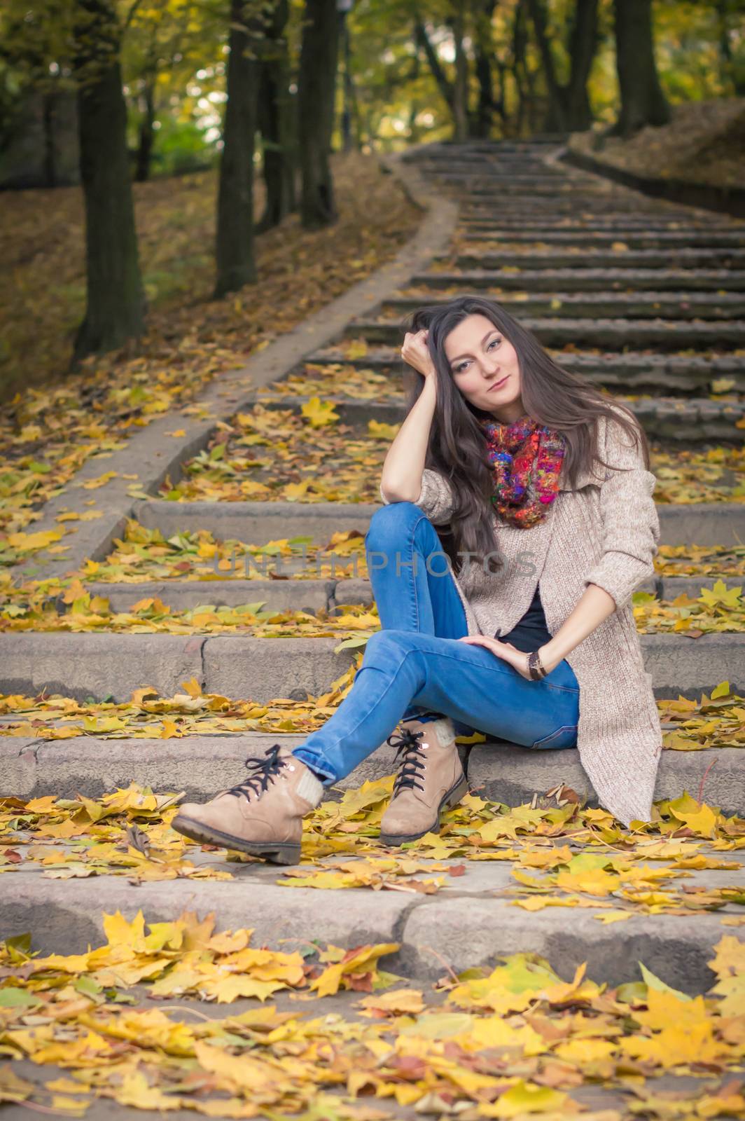 girl sitting on stone steps in autumn Park