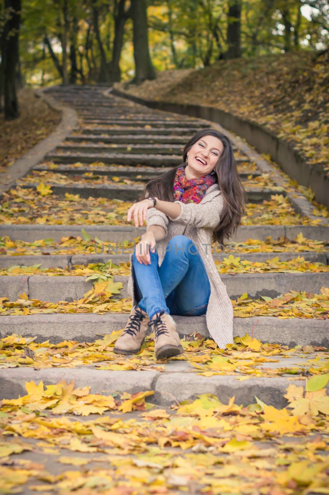 girl sitting on stone steps in autumn Park