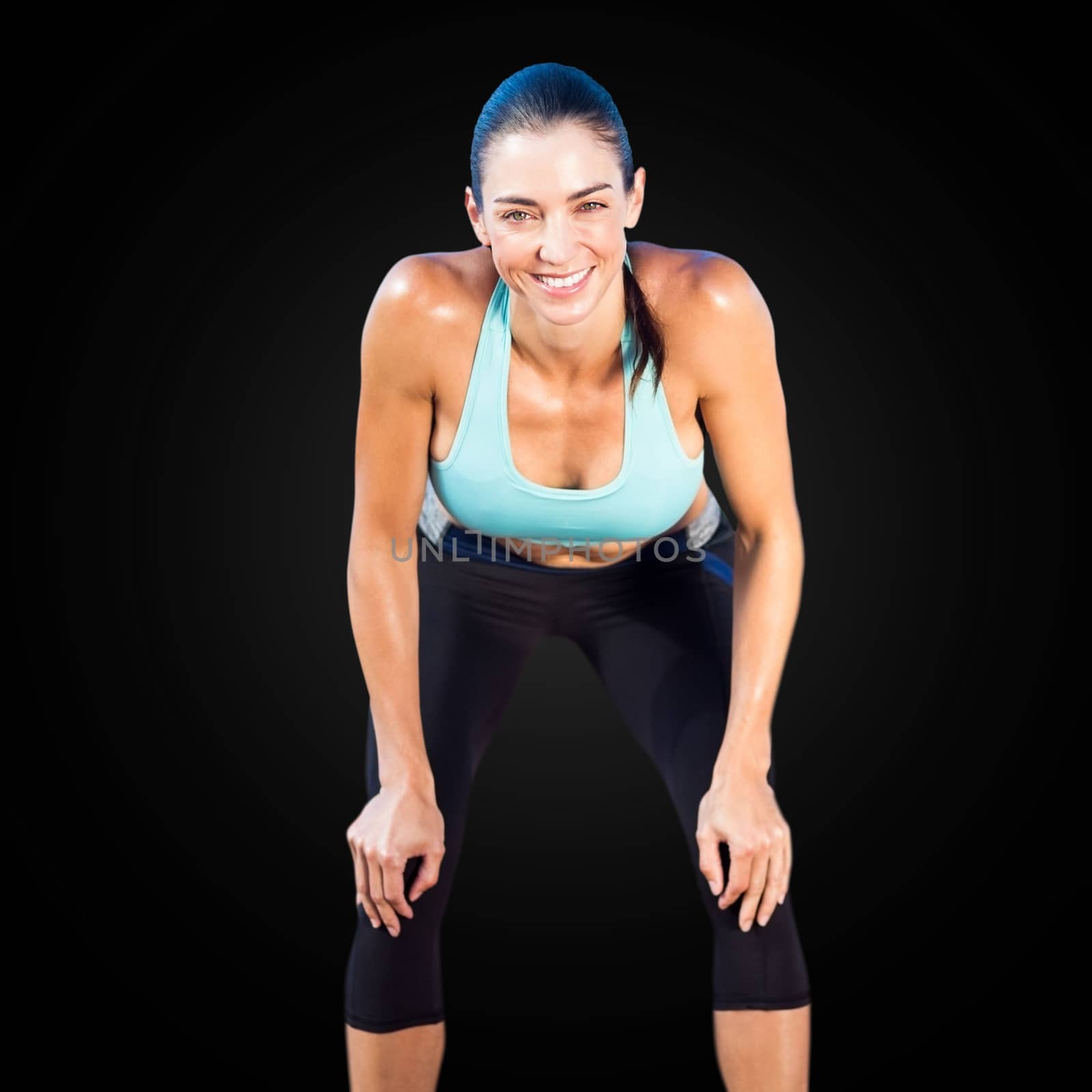 Sportswoman posing his hands on knee in a black background 