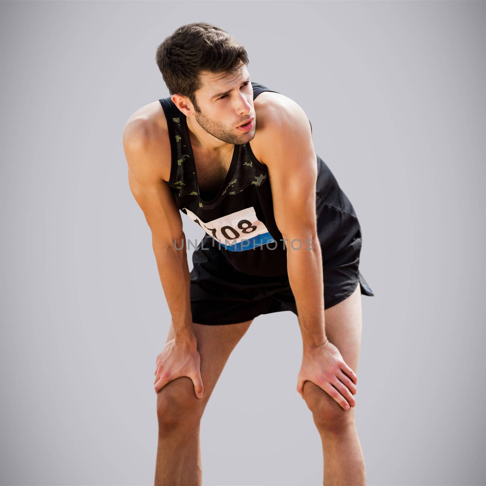 Athletic man resting with hands on knees against light grey
