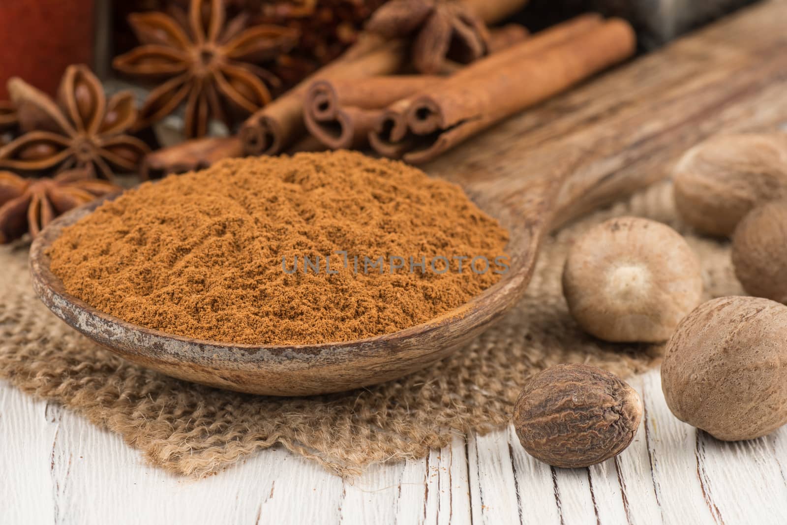Ground cinnamon in a wooden spoon on the old wooden background. Selective focus.